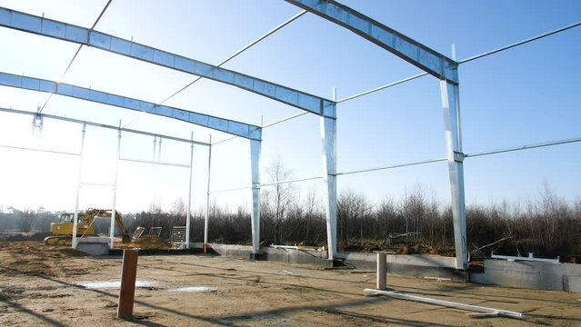 Construction site with foundations pillars made of alternative eco friendly sustainable materials, under sunny dat in countryside with yellow crane excavator working in background