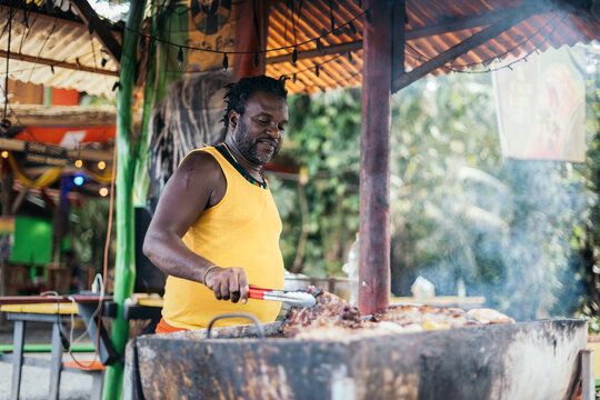 Afro-Caribbean man cooking on a barbeque