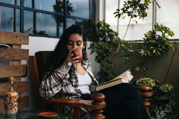 Young woman reading and drinking tea