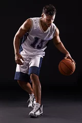 Gardinen Dribbling pro. Studio shot of a basketball player against a black background. © Duncan M/peopleimages.com