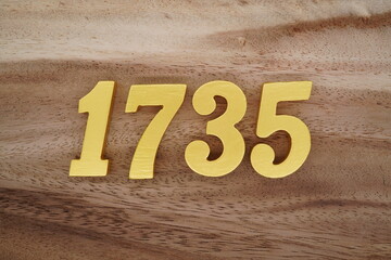 Golden Arabic numerals on a real brown and white wooden floor number 1735