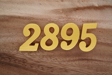 Golden Arabic numerals on a real brown and white wooden floor number 2895