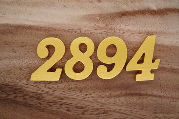 Golden Arabic numerals on a real brown and white wooden floor number 2894