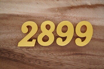 Golden Arabic numerals on a real brown and white wooden floor number 2899