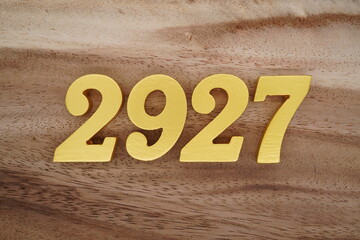 Golden Arabic numerals on a real brown and white wooden floor number 2927