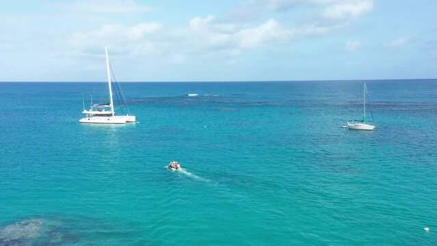 Motorboat transporting people to Catamaran for trip on Caribbean Sea during sunny day with blue water and sky - Dominican Republic, Playa Punta Popy