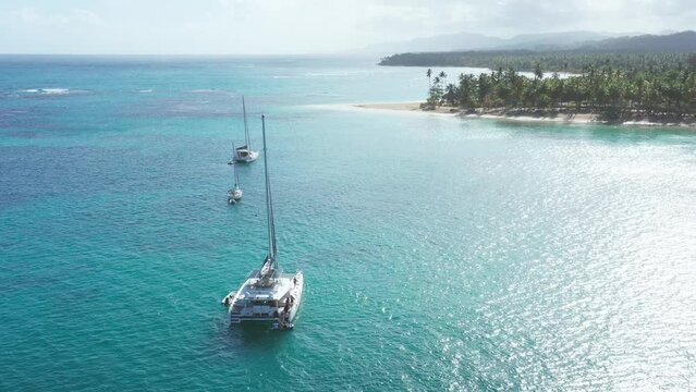 Luxurious boats anchored at Playa Punta Popy, Las Terrenas in Dominican Republic. Aerial backward