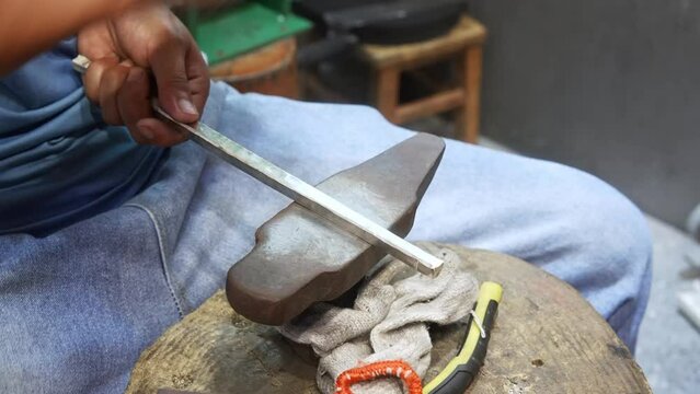 silversmith beating silver bar with hammer
