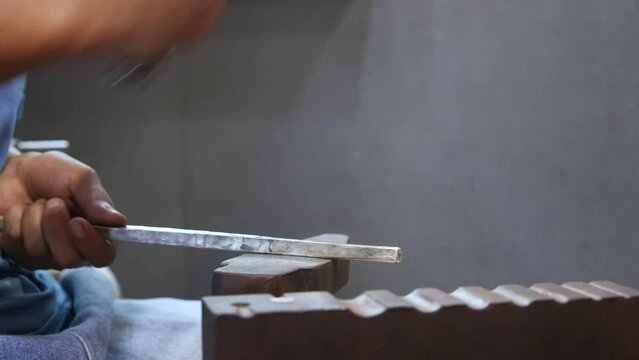 silversmith beating silver bar with hammer
