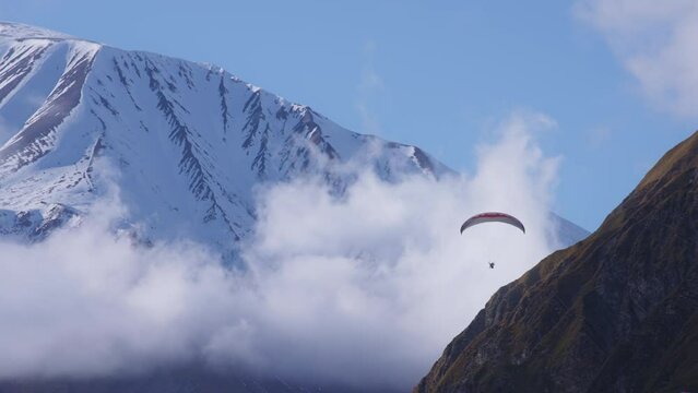 Parachute sky-diver flying between clouds and mountains. Slow motion. 