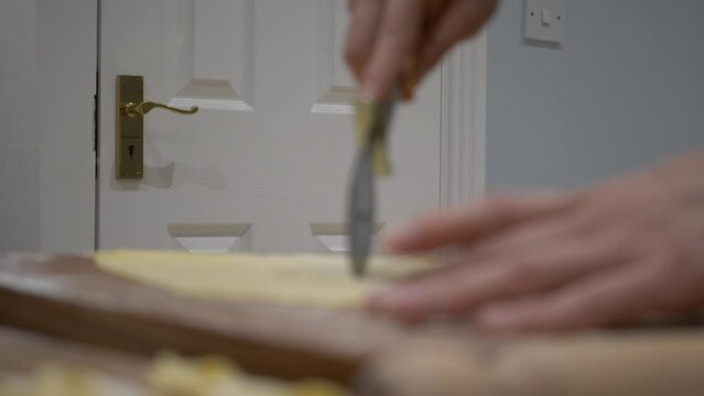 Racking Focus Shot Of Baker's Hands Cutting Faworki Dough With Pizza Cutter. White Wooden Door In Background. close up