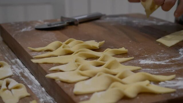 Hands Tiwisting Dough Into Ribbon Shapes. Making Faworki (Angel Wings) In Poland. close up