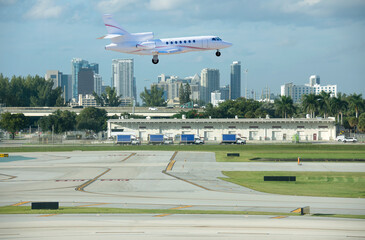 Large luxury commercial passenger private jet airline plane landing or taking off at Fort Lauderdale International Airport with cityscape in background on a sunny afternoon. - 493384051