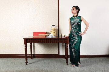 Beautiful young woman wearing modern Chinese style dress cheongsam fashion retro vintage table room