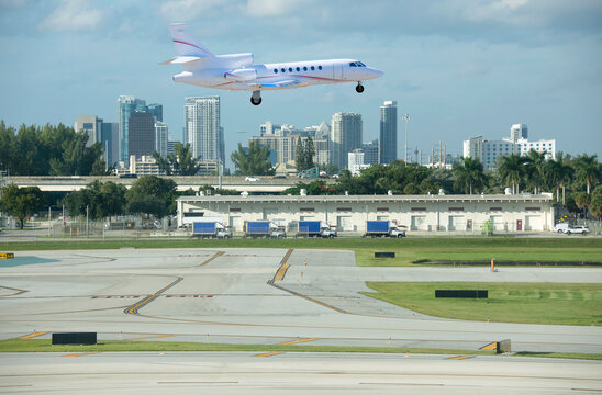 Large luxury commercial passenger private jet airline plane landing or taking off at Fort Lauderdale International Airport with cityscape in background on a sunny afternoon.