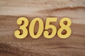 Golden Arabic numerals on a real brown and white wooden floor number 3058