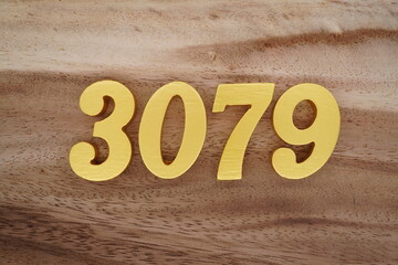 Golden Arabic numerals on a real brown and white wooden floor number 3079