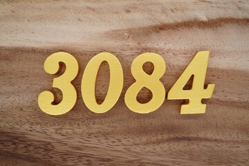 Golden Arabic numerals on a real brown and white wooden floor number 3084
