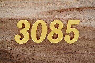 Golden Arabic numerals on a real brown and white wooden floor number 3085