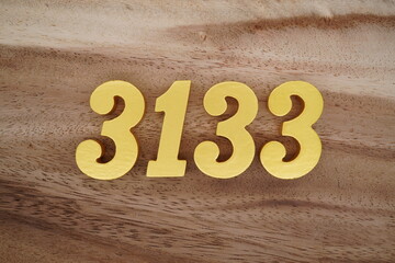 Golden Arabic numerals on a real brown and white wooden floor number 3133