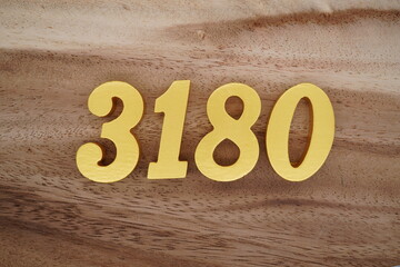 Golden Arabic numerals on a real brown and white wooden floor number 3180