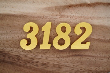Golden Arabic numerals on a real brown and white wooden floor number 3182