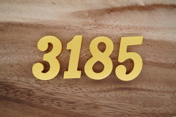 Golden Arabic numerals on a real brown and white wooden floor number 3185