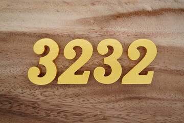 Golden Arabic numerals on a real brown and white wooden floor number 3232