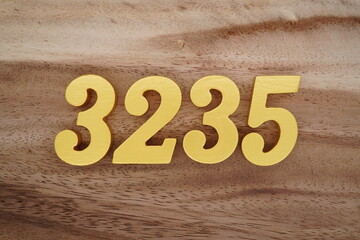 Golden Arabic numerals on a real brown and white wooden floor number 3235