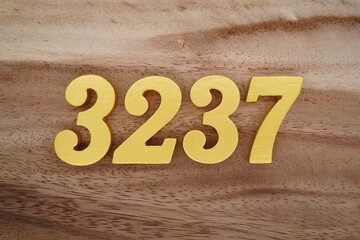 Golden Arabic numerals on a real brown and white wooden floor number 3237