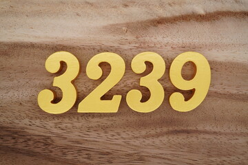 Golden Arabic numerals on a real brown and white wooden floor number 3239