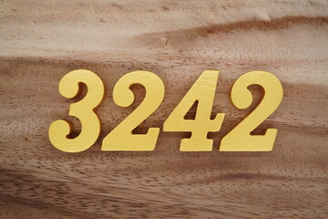 Golden Arabic numerals on a real brown and white wooden floor number 3242