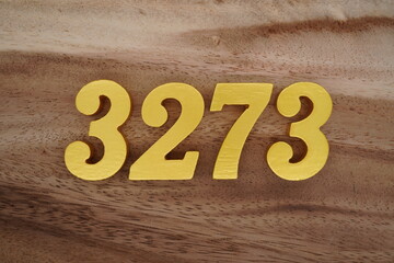 Golden Arabic numerals on a real brown and white wooden floor number 3273