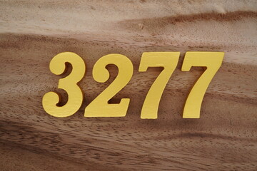 Golden Arabic numerals on a real brown and white wooden floor number 3277