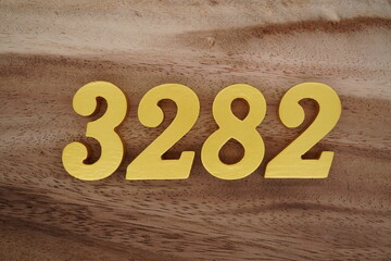 Golden Arabic numerals on a real brown and white wooden floor number 3282