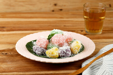 Colorful Ongol-Ongol or Sentiling, Steamed Cassava Cake Coating with Grated Coconut, Served on Ceramic Plate