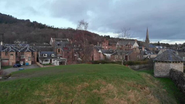 Drone footage. Flying from behind a small hill, ascending over the town of Callander, Scotland, Highlands