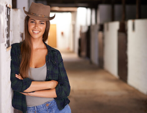 Im a stable girl. A portrait of a beautiful young cowgirl leaning against a wall in a stable.