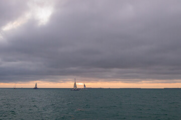 Storm clouds over the ocean with sailboat and Catamaran on horizon

