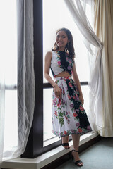 Beautiful young woman wearing modern cheongsam inspired dress standing posing next to window light