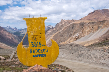 Stella on the road to Kumtor gold mine with inscription Barskoon mountain pass.