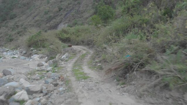 Mountain dirt road vehicle tracks leading out to riverbed opening boulders rocks sand i valley Kabayan Benguet Philippines fast reverse reveal aerial