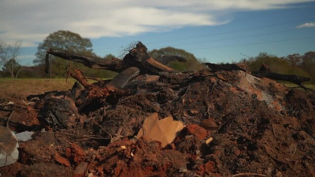 Smoldering slash pile of dirt, debris, and lumbar smoking after a giant bonfire to clear out land for farming