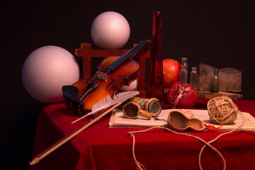 Still life with violin and different objects on the red table