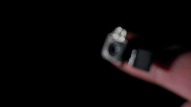 A hidden camera module that fits on a finger on a black background disappears