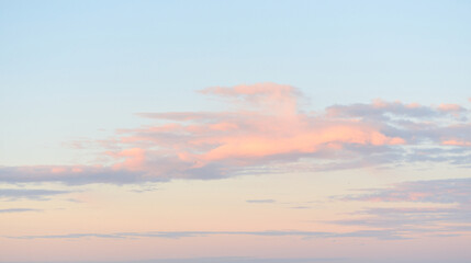 Clear blue sky with glowing pink cirrus and cumulus clouds after storm at sunset. Dramatic...