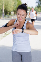 female runner looking at wristwatch and feeling her pulse
