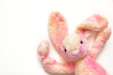 Cute soft bunny toy on white background. Easter pink bunny with egg