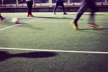 夜のフットサルコートでプレーする人々の足元