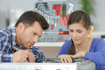 woman looking at male worker repairing washing machine